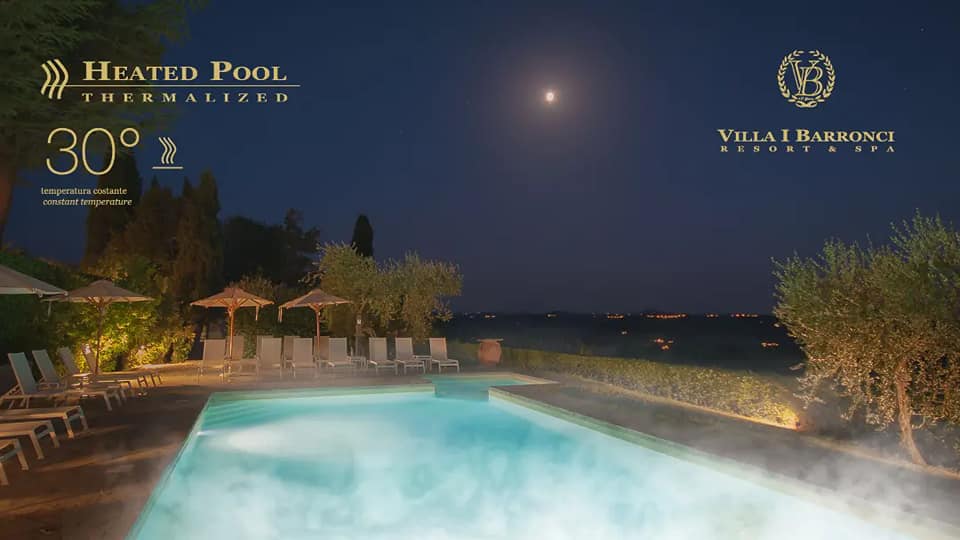 The heated pool at night under a starlit sky, framed by olive trees